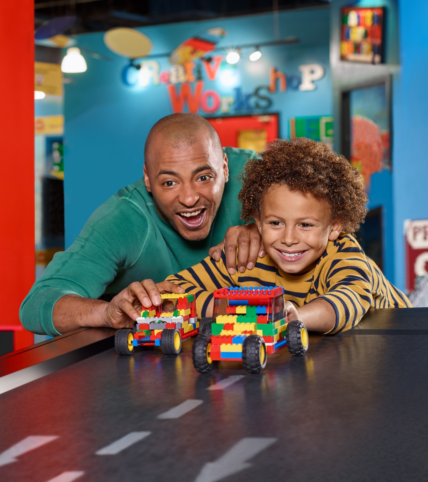 A father and sun racing their LEGO cars down a ramp.
