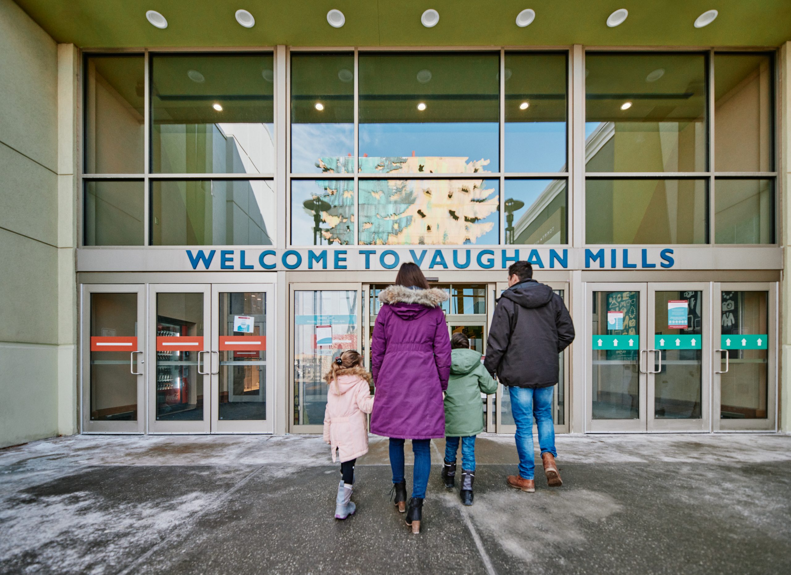 A family of four walking into the entry doors at Vaughan Mills