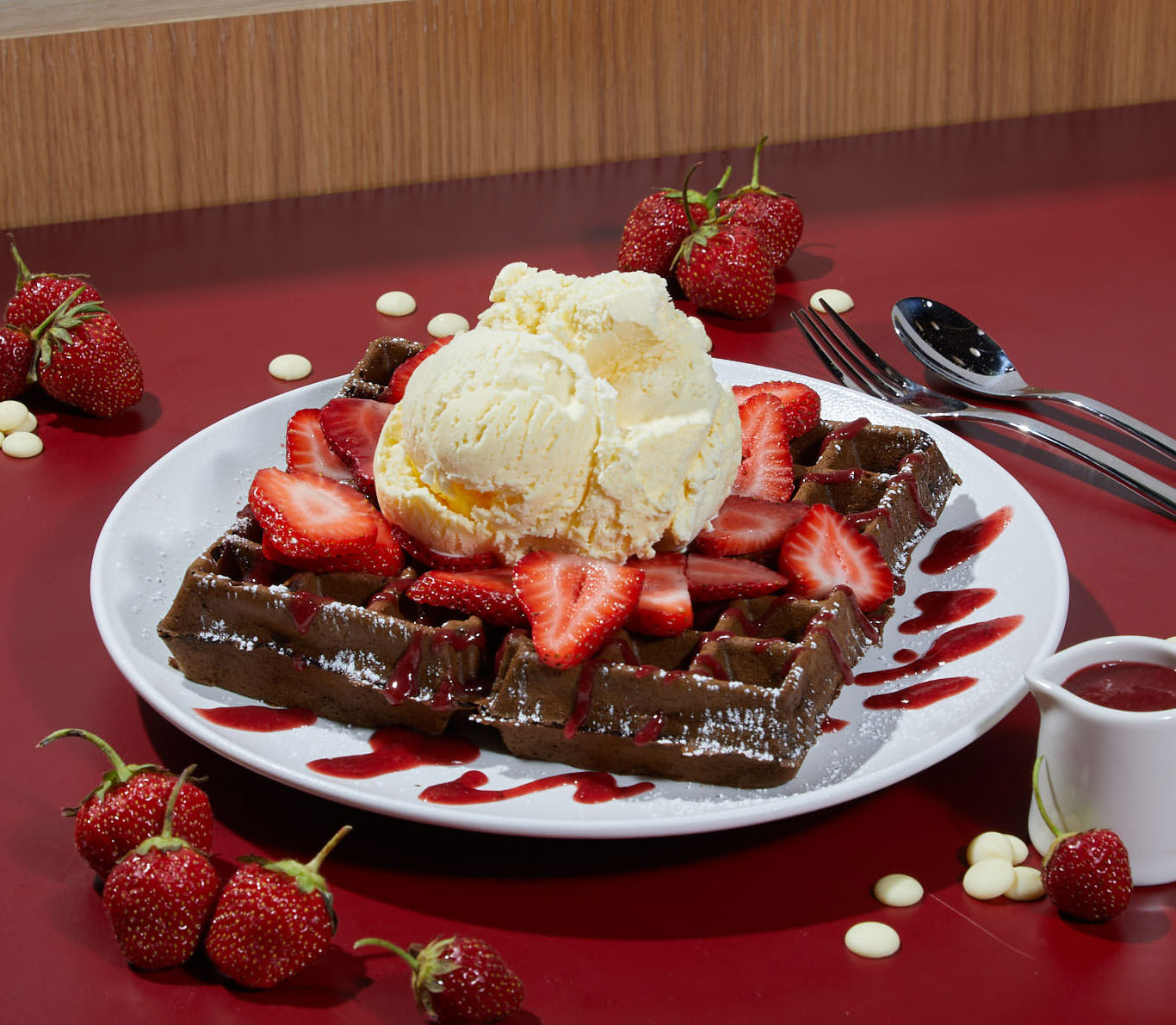 Chocolate waffle topped with strawberries and ice cream.