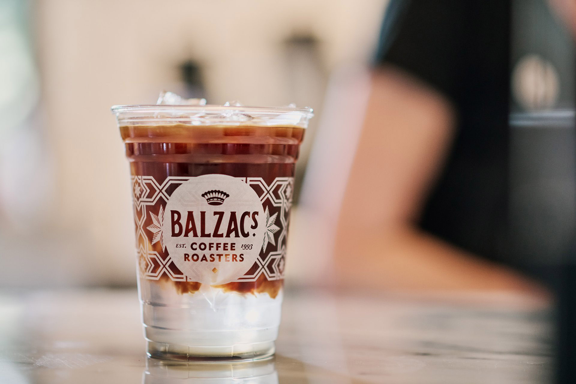 An iced coffee in a Balzac's branded cup on a countertop.