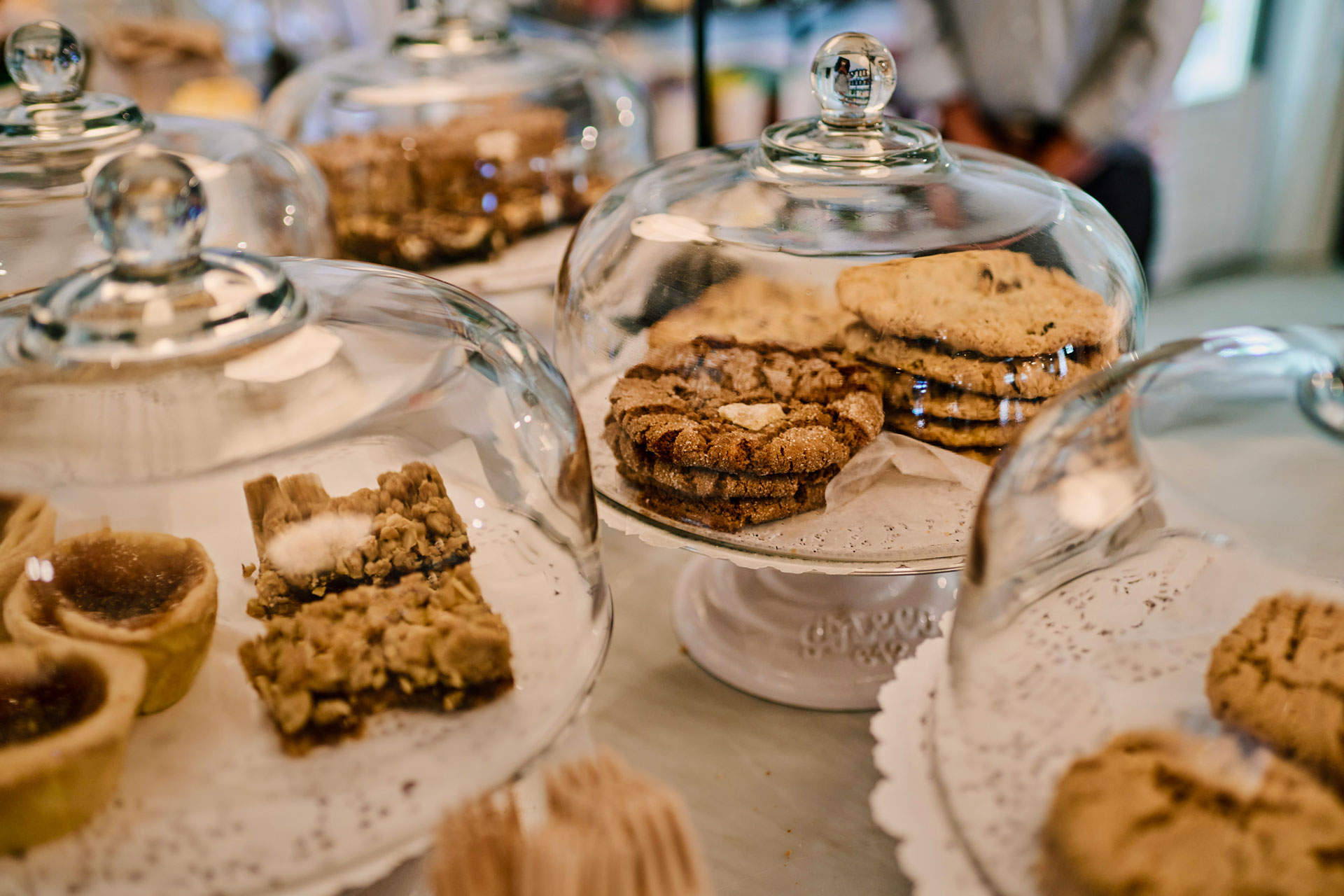 Glass-covered dishes with various cookies and pastries inside.