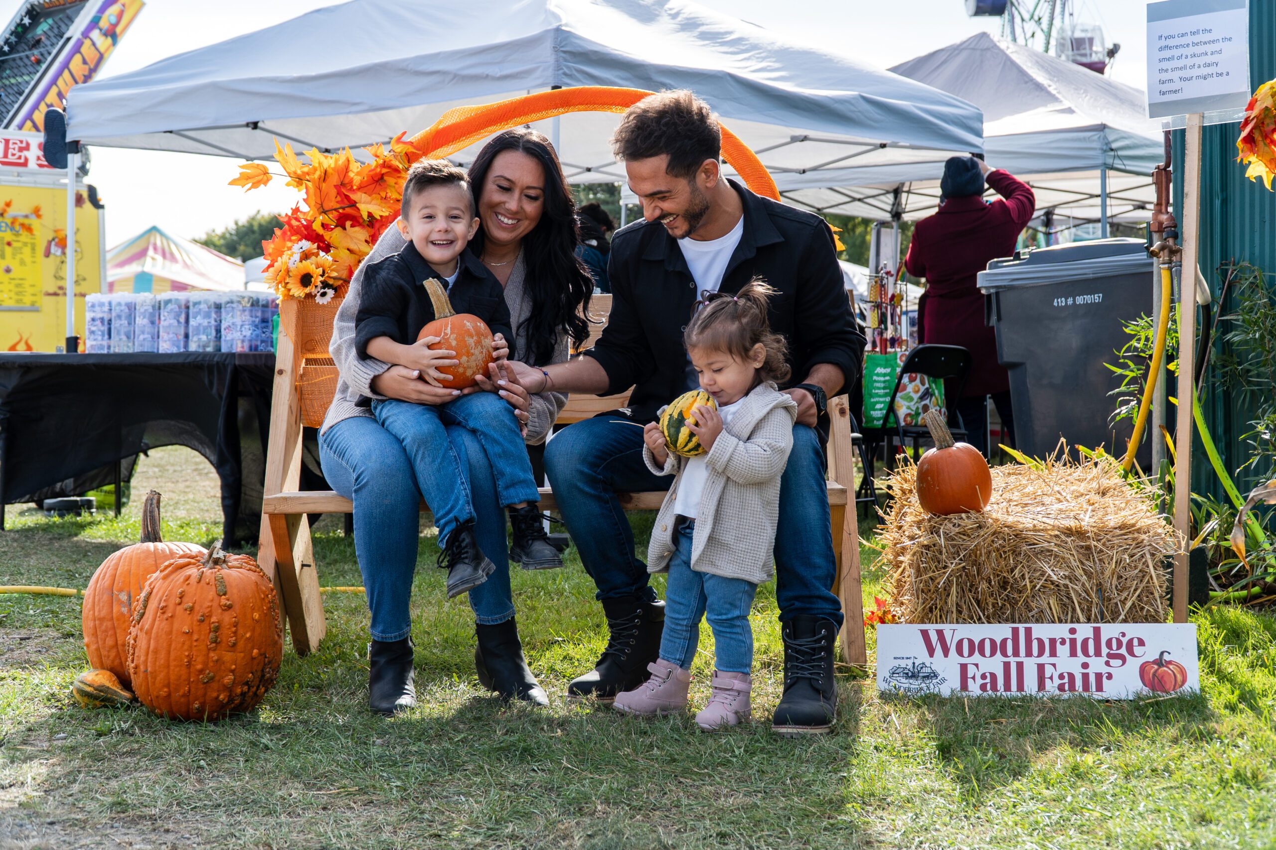 A family posing in front of the Woodbridge Fall Fair photo back drop
