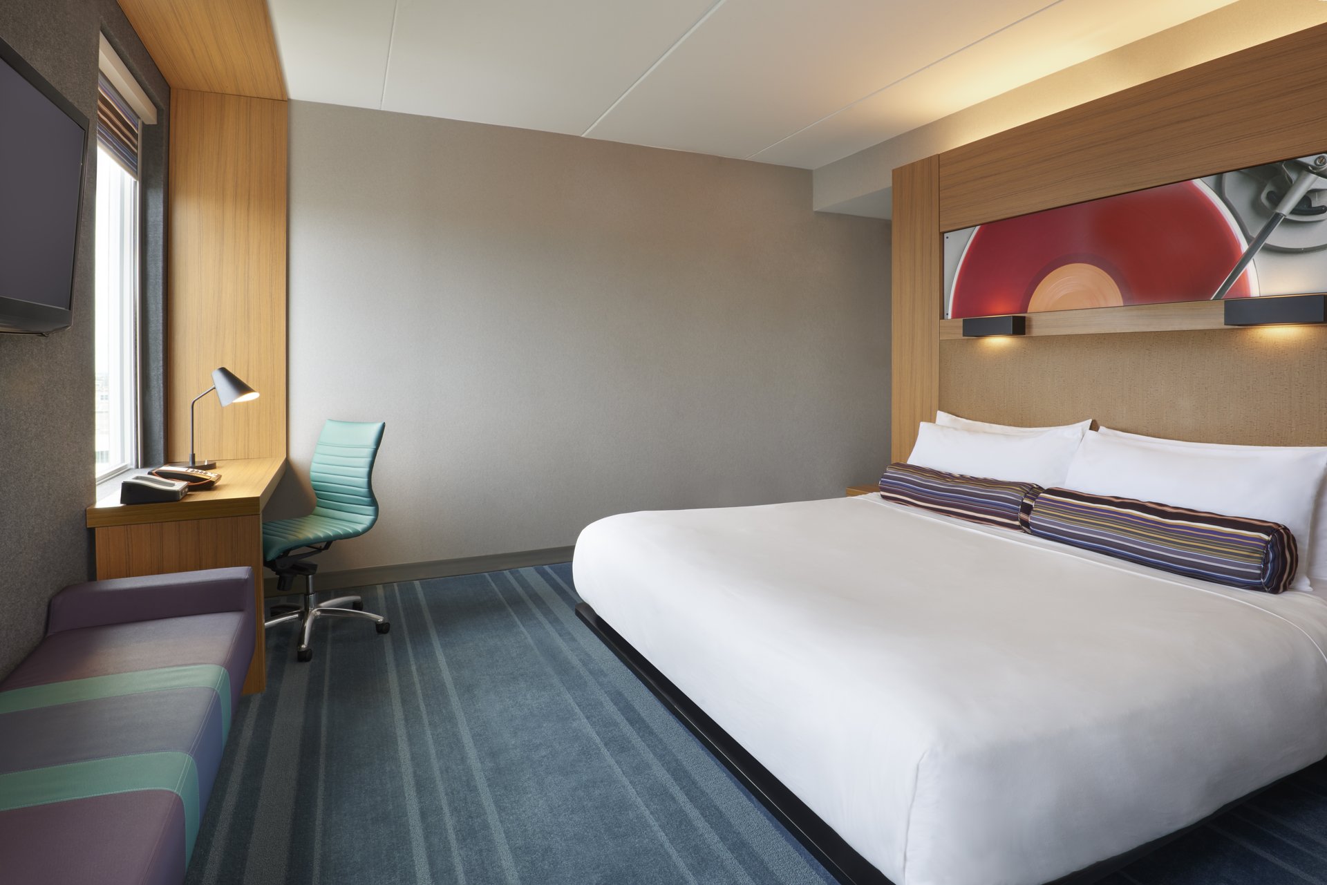 A hotel room with a king size bed and blue carpet