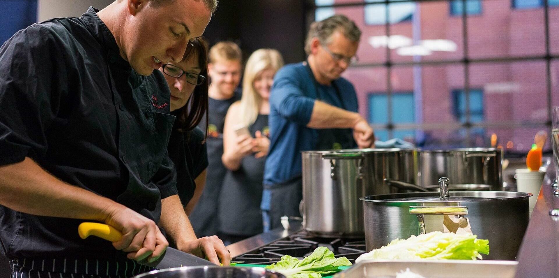Image of a chef chopping vegetables while leading an adult cooking class