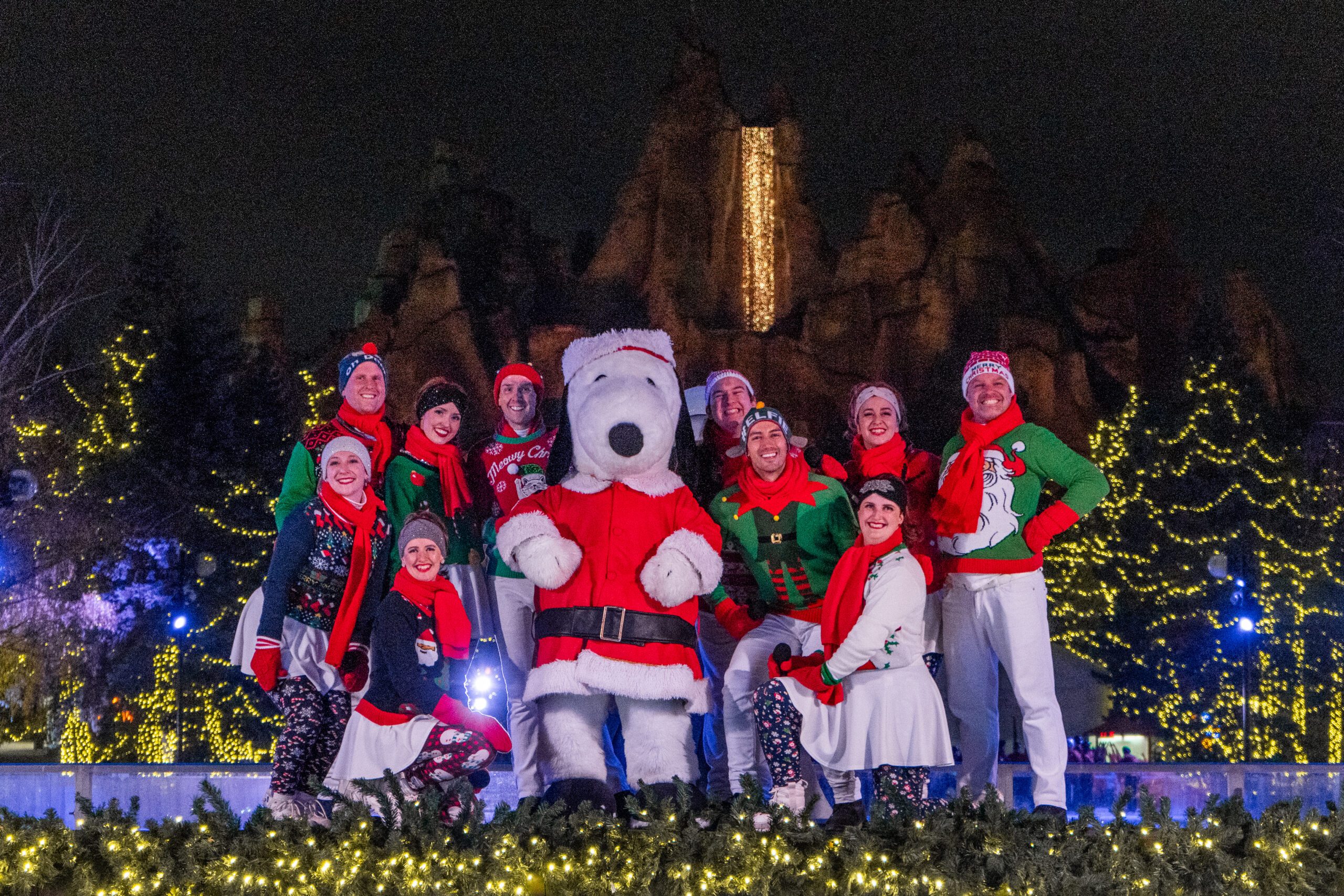 Image of a group of people dressed like Christmas elves posing for a group photo with a person dressed as a polar bear mascot