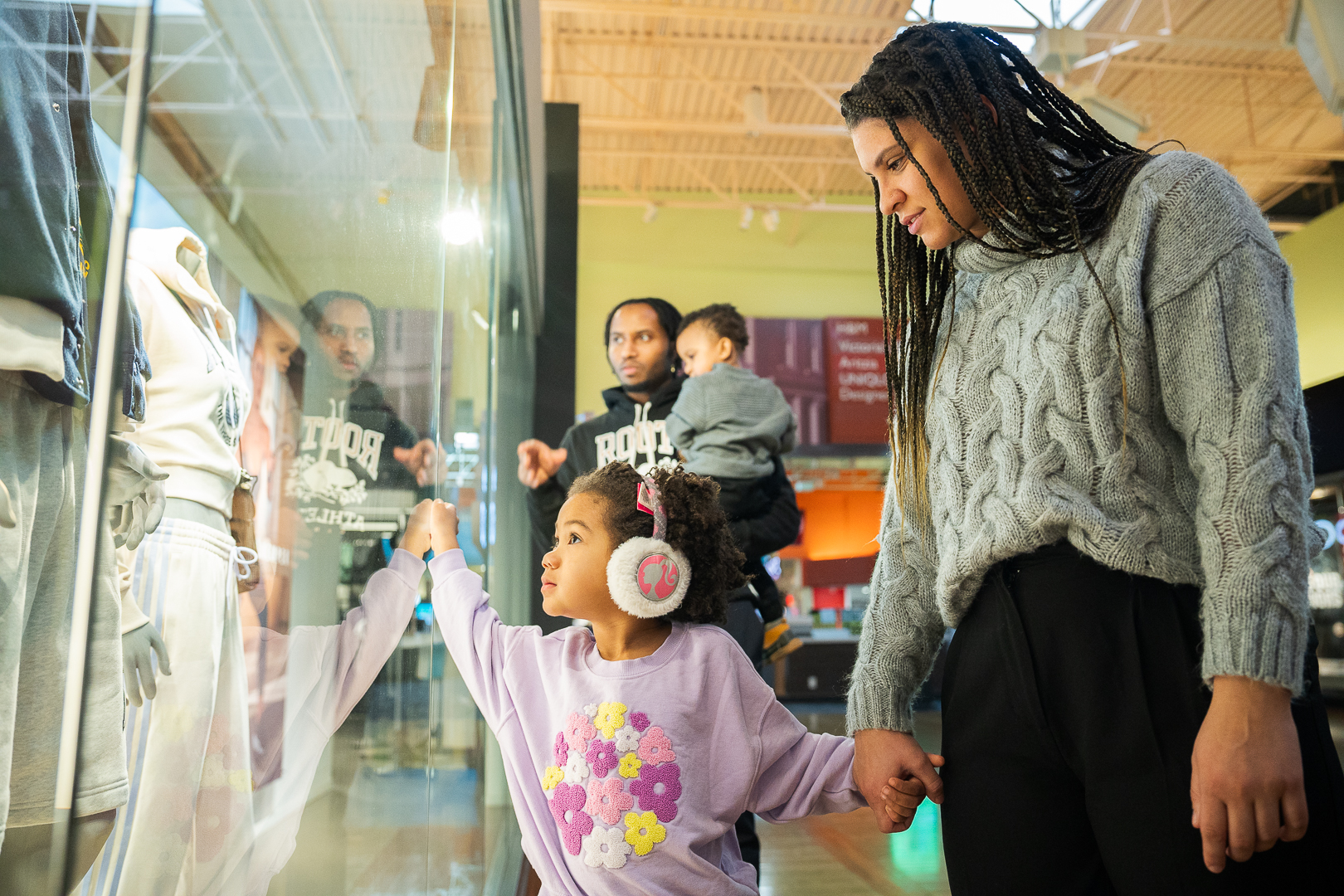 A family of four looking in the windows of shops at a mall