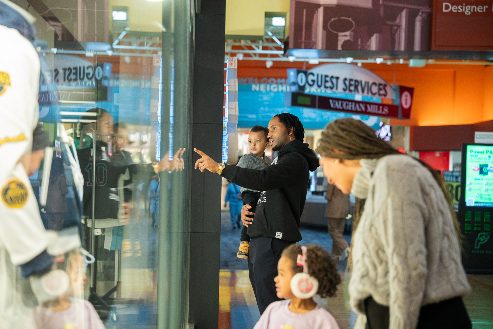 A family with two small children stop to look at the window displays in a shopping mall