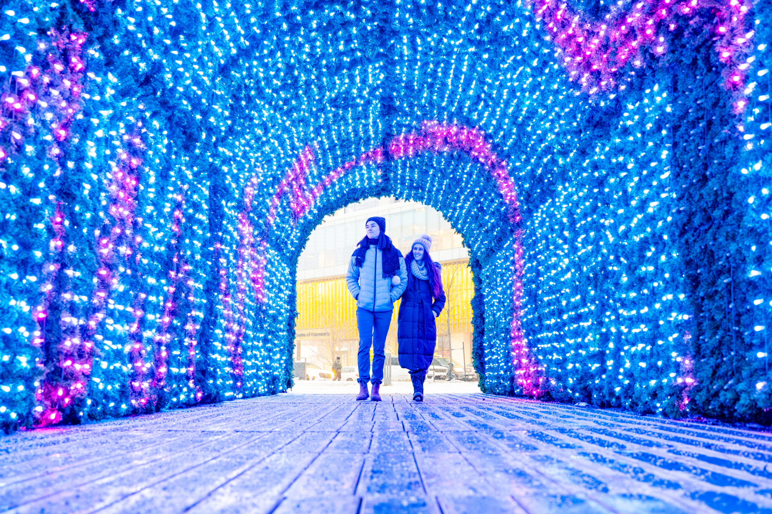 a couple walking through the VMC light-up tree, Christmas lights surrounding