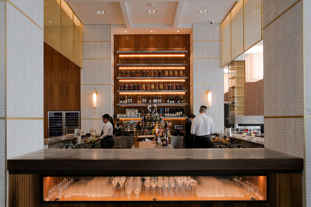 Image of the interior of a beautifully designed restaurant. Staff are seen working behind a bar.