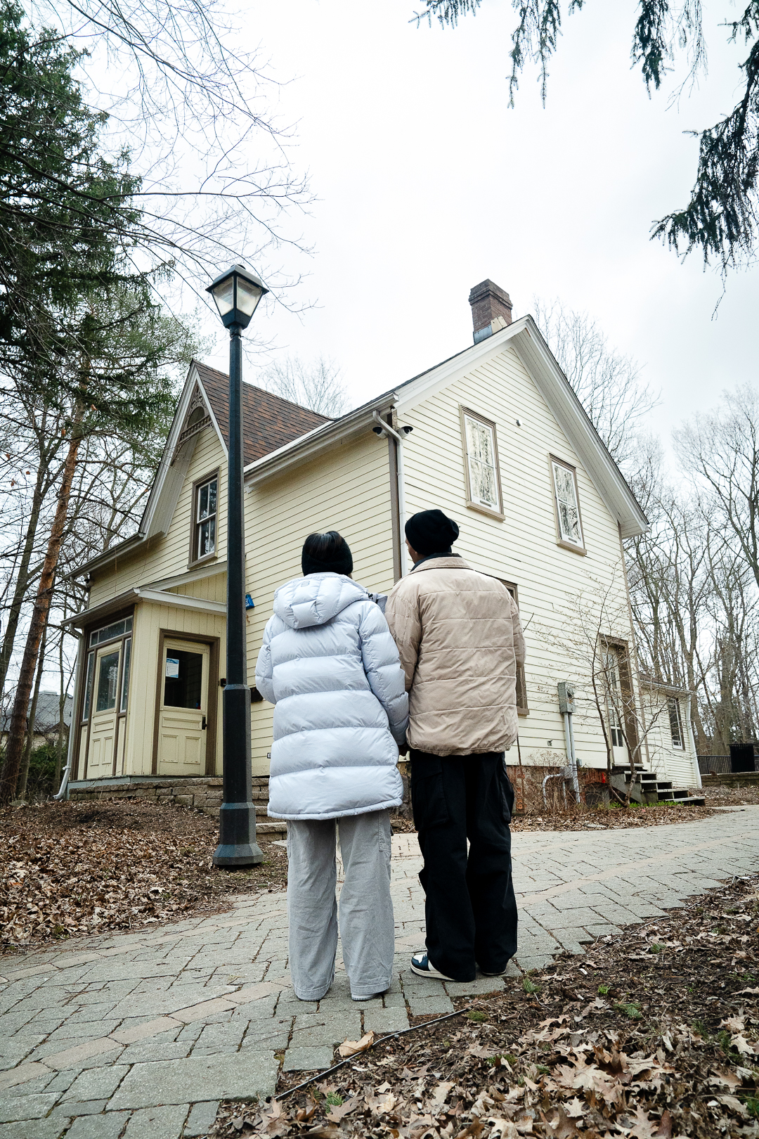 Image of two people standing on a walkway looking at a beautiful heritage home.