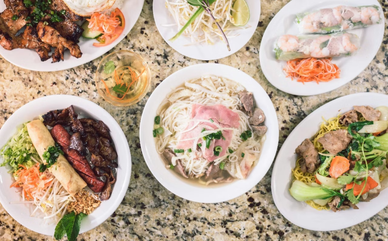 Image taken from above of a counter with a bowl of pho and bowls containing garnishes beside it