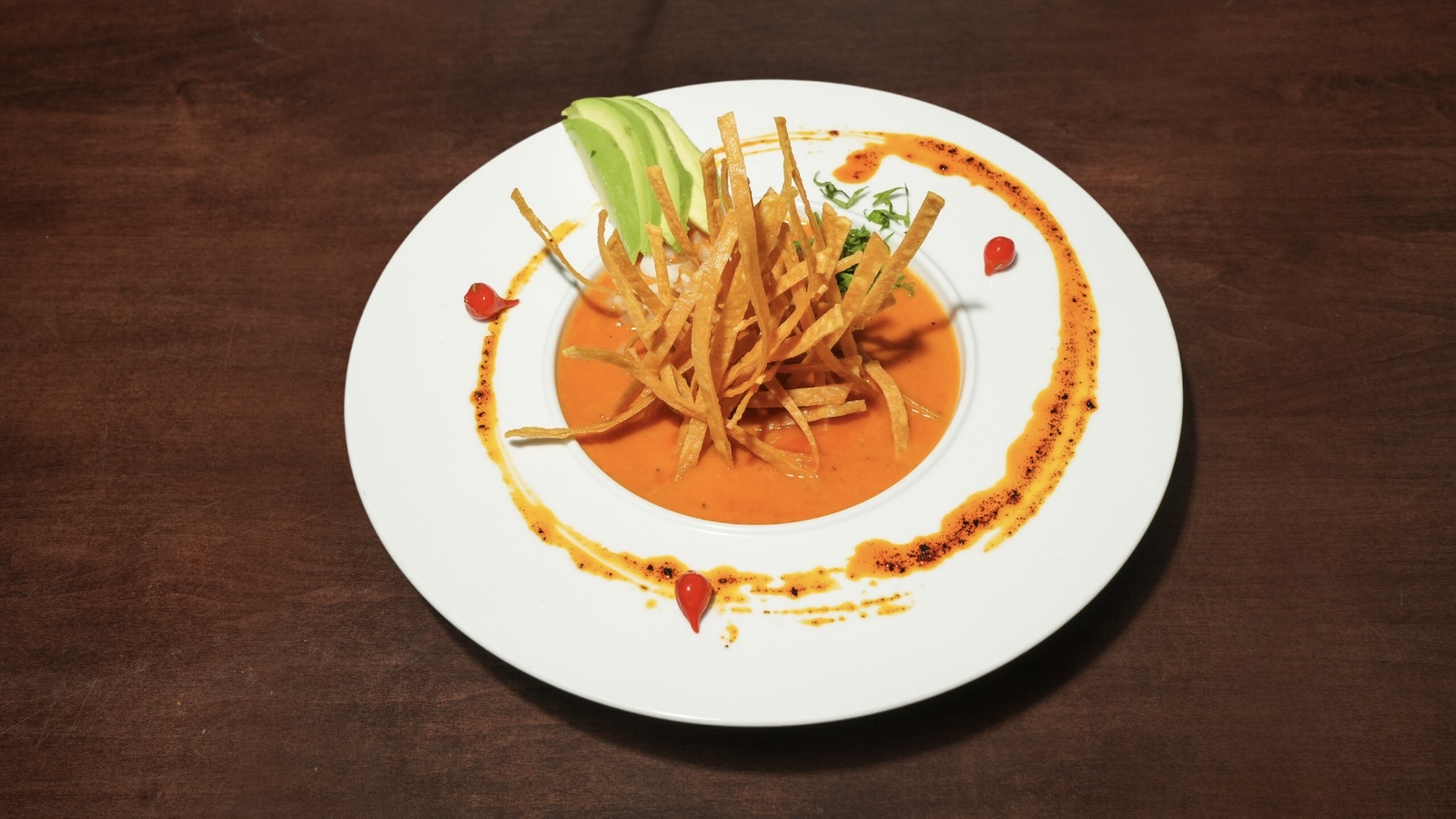 Image of a bowl of tortilla soup garnished with a lime wedge and crispy tortilla strips