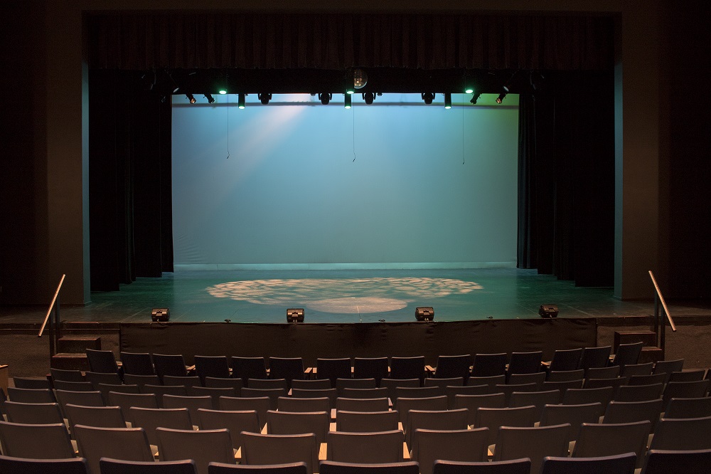 Image of an empty theatre stage taken from the back rows of seating