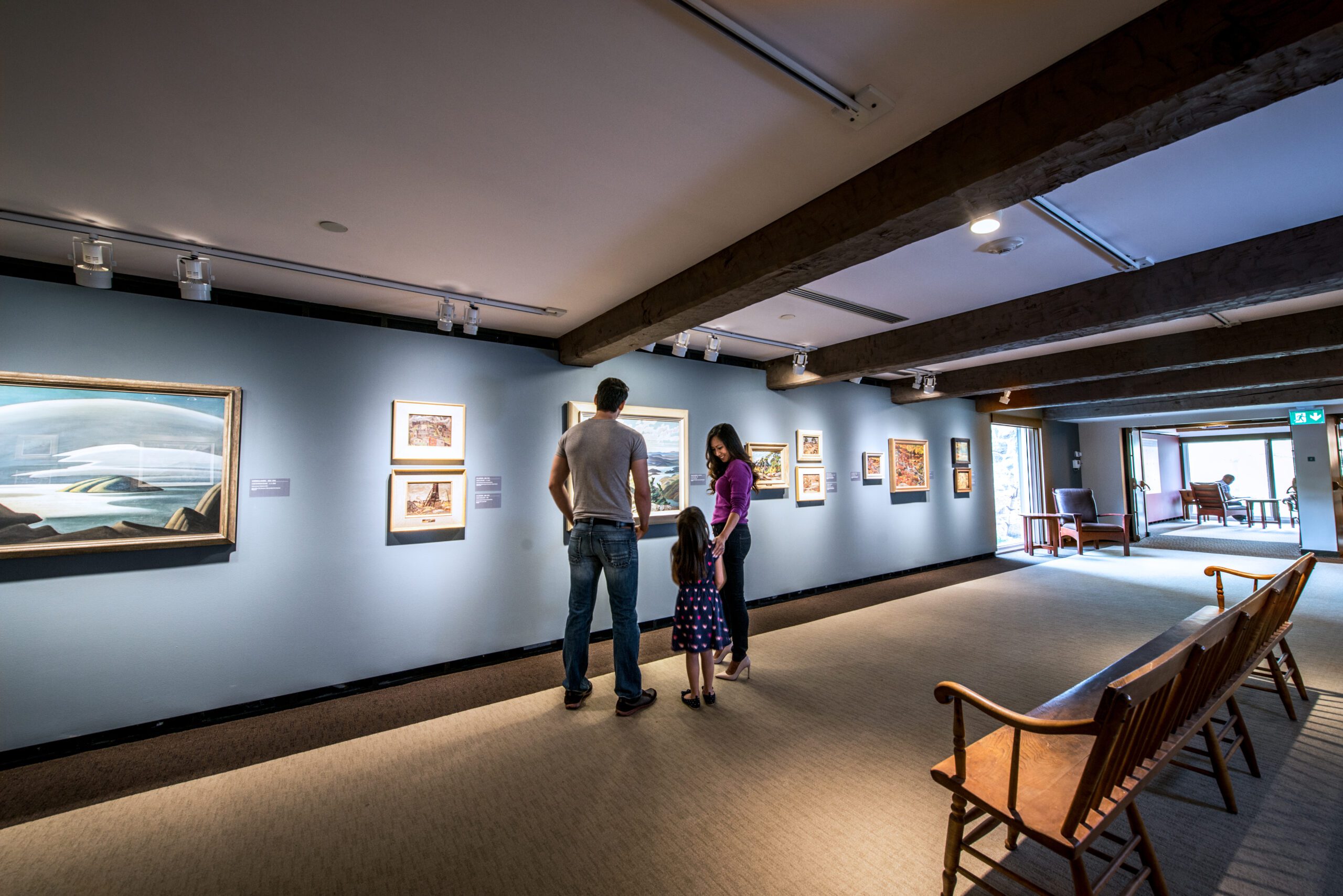 Image of a family of three in an art gallery that has stopped to look at a painting