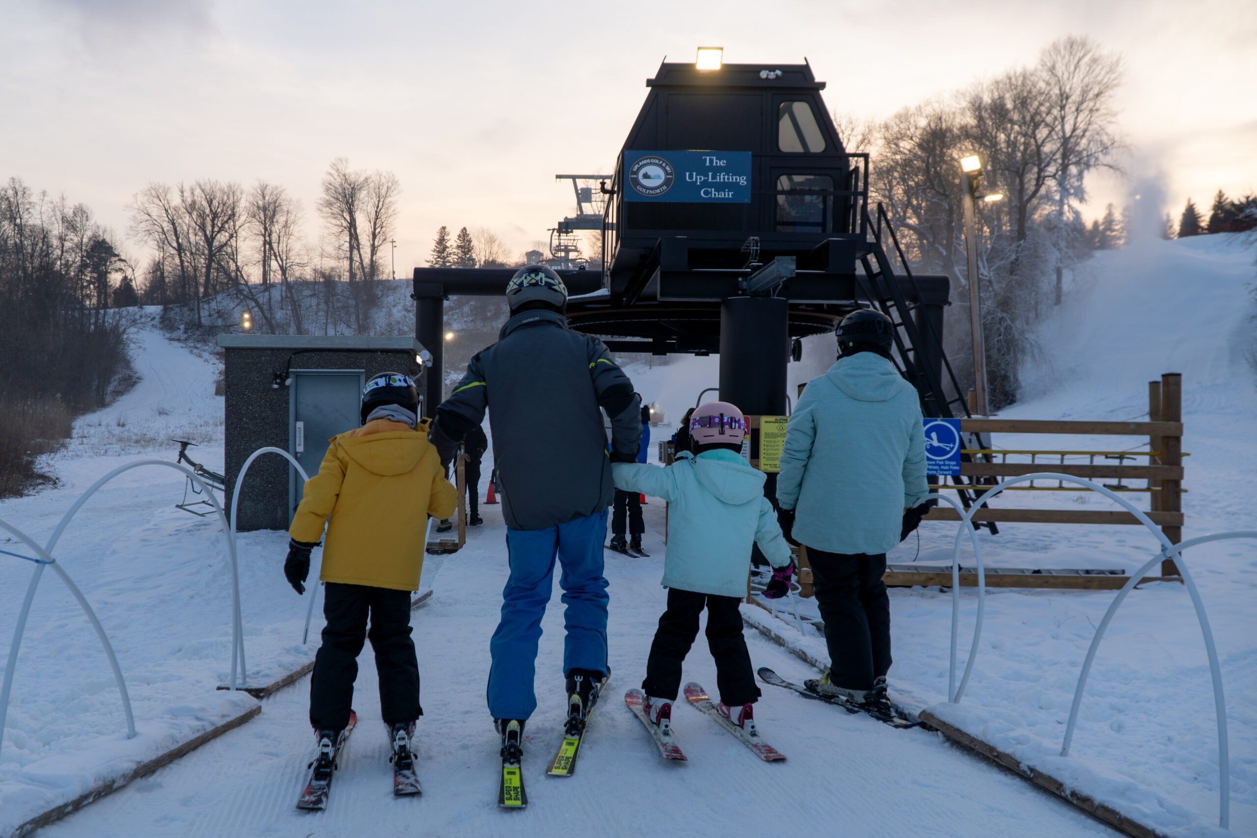 Image of a family of four waiting in line for a chair lift at a ski hill