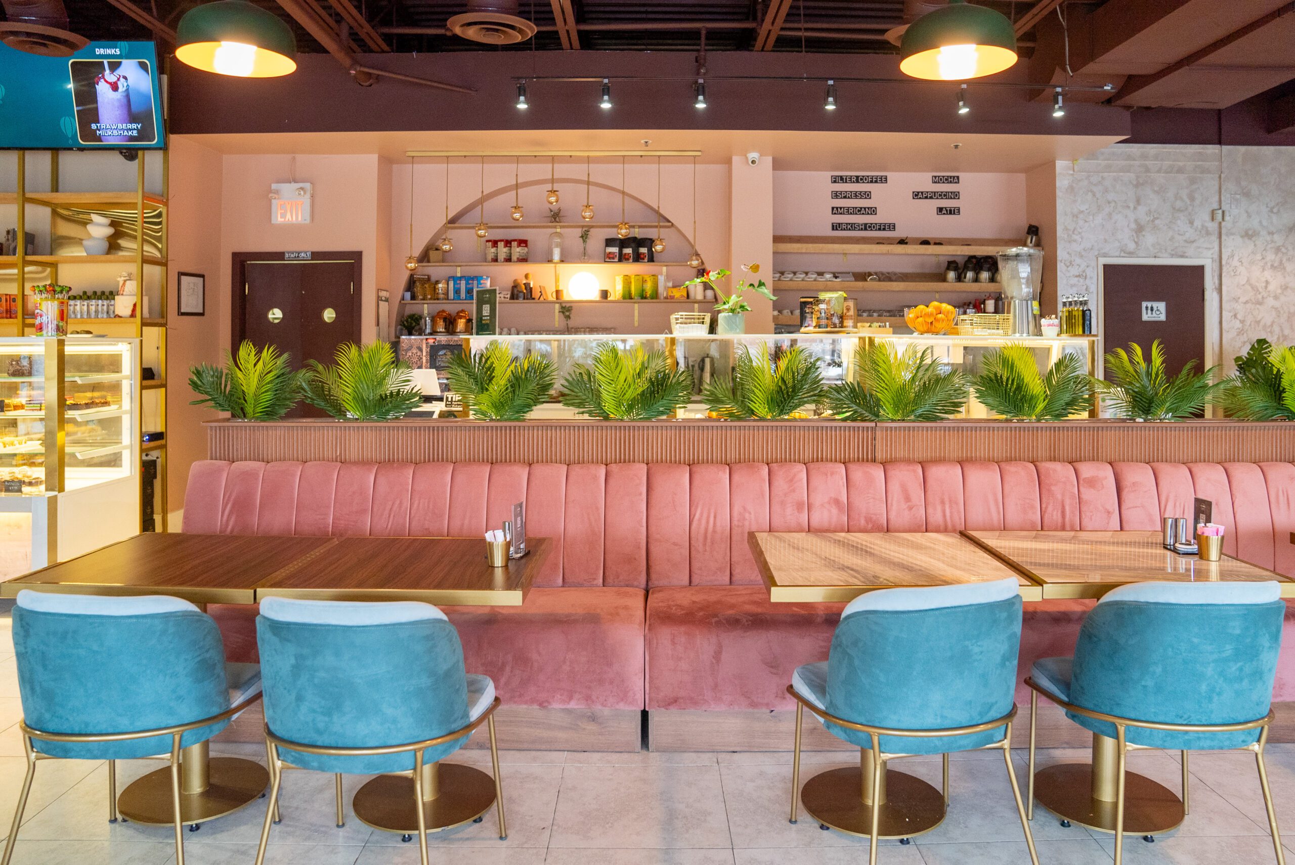 Image of a beautifully decorated cafe with cozy bench seating in the foreground and a counter with display case in the background