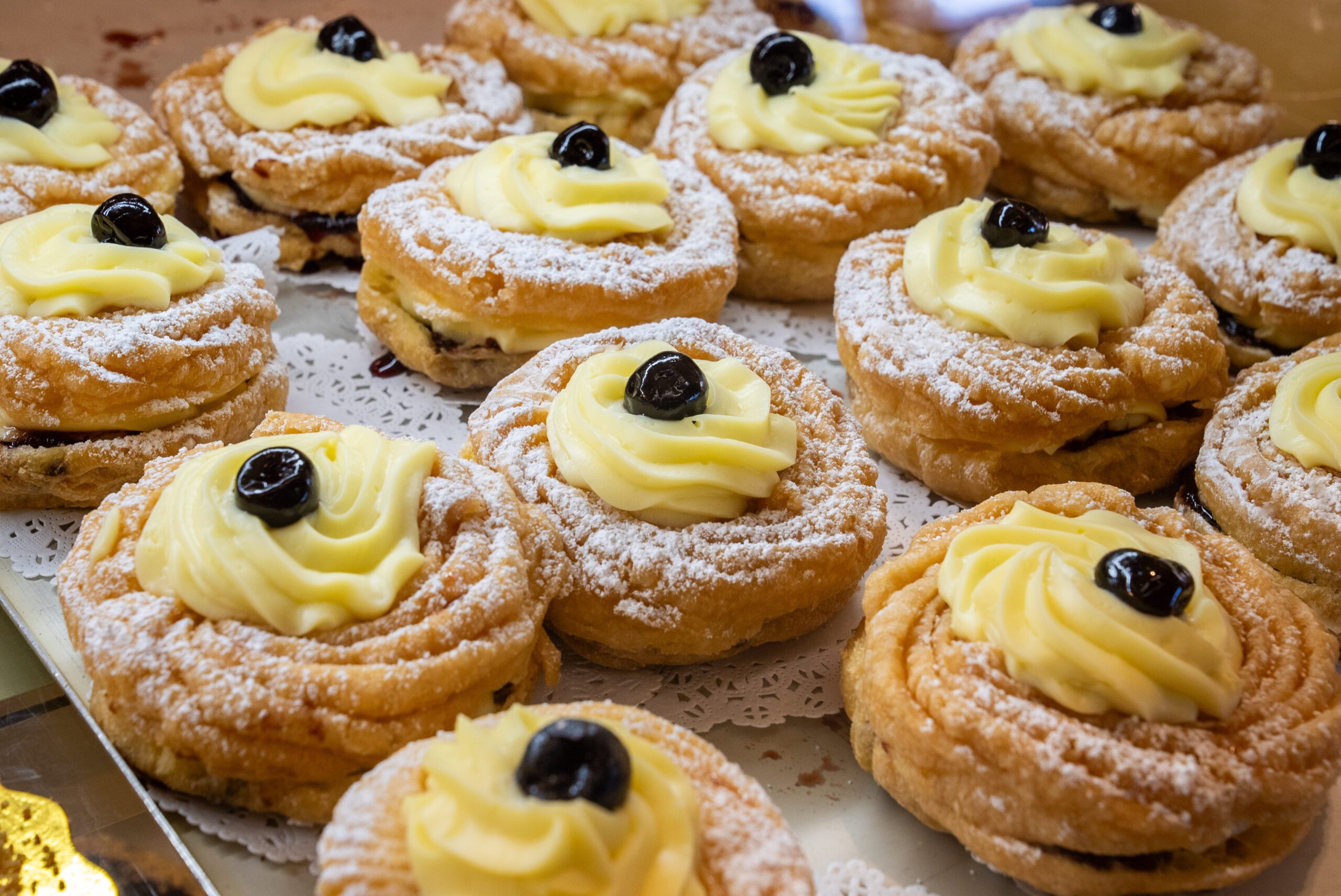 Image of pastries topped with custard and a blueberry lined up in a display case