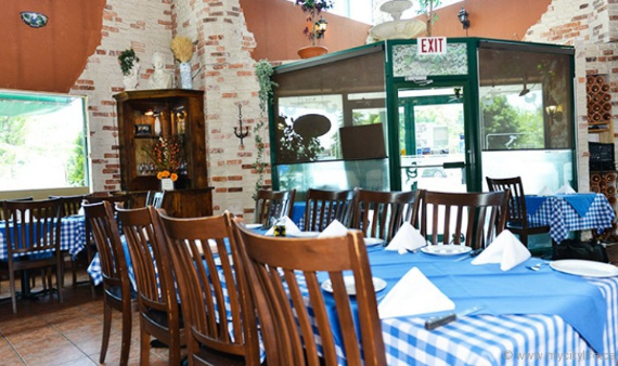 Image of the interior of a cozy Italian restaurant where the tables are all set with tablecloths and folded napkins