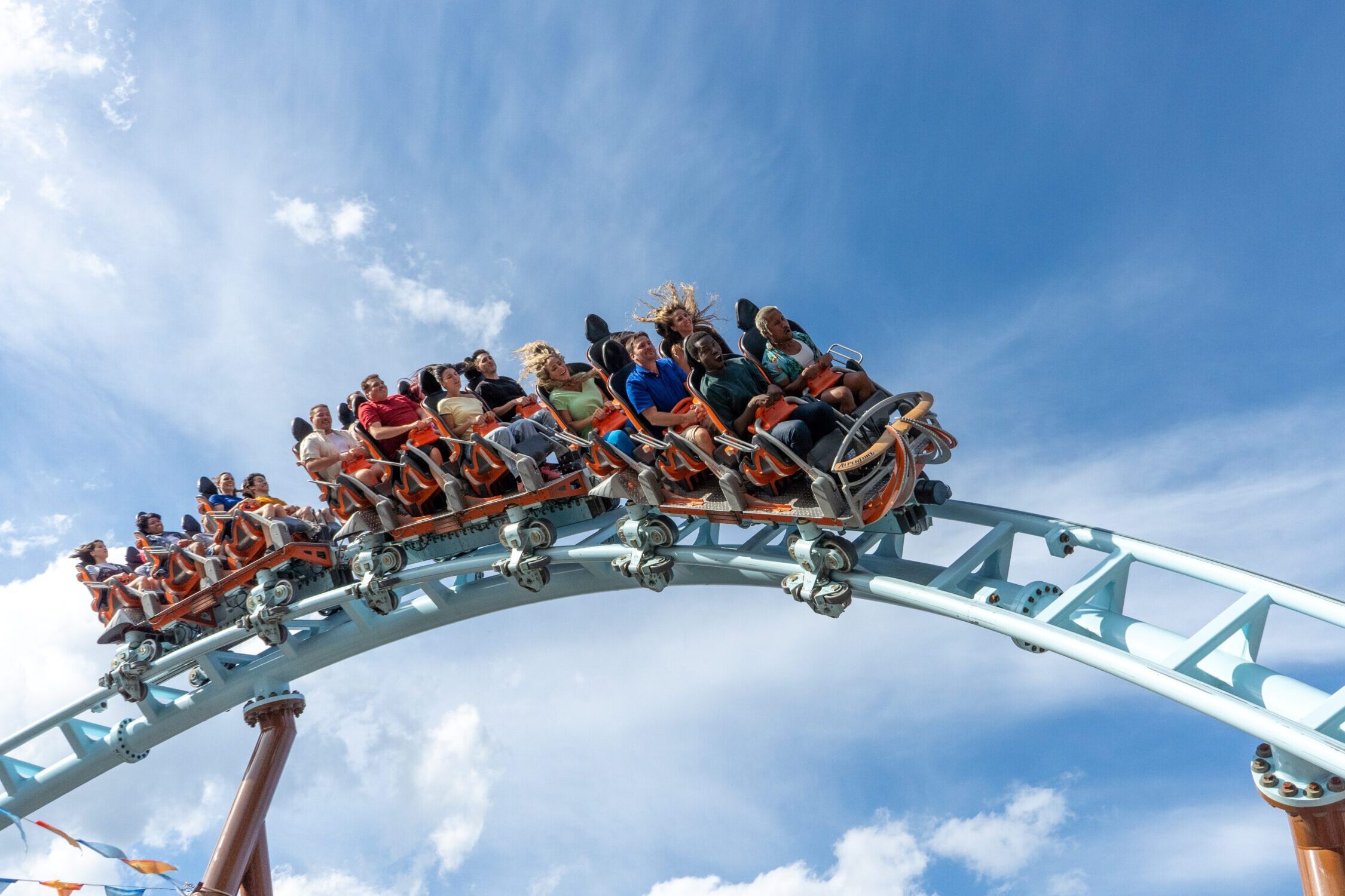 Image of people riding a rollercoaster with a blue sky behind them