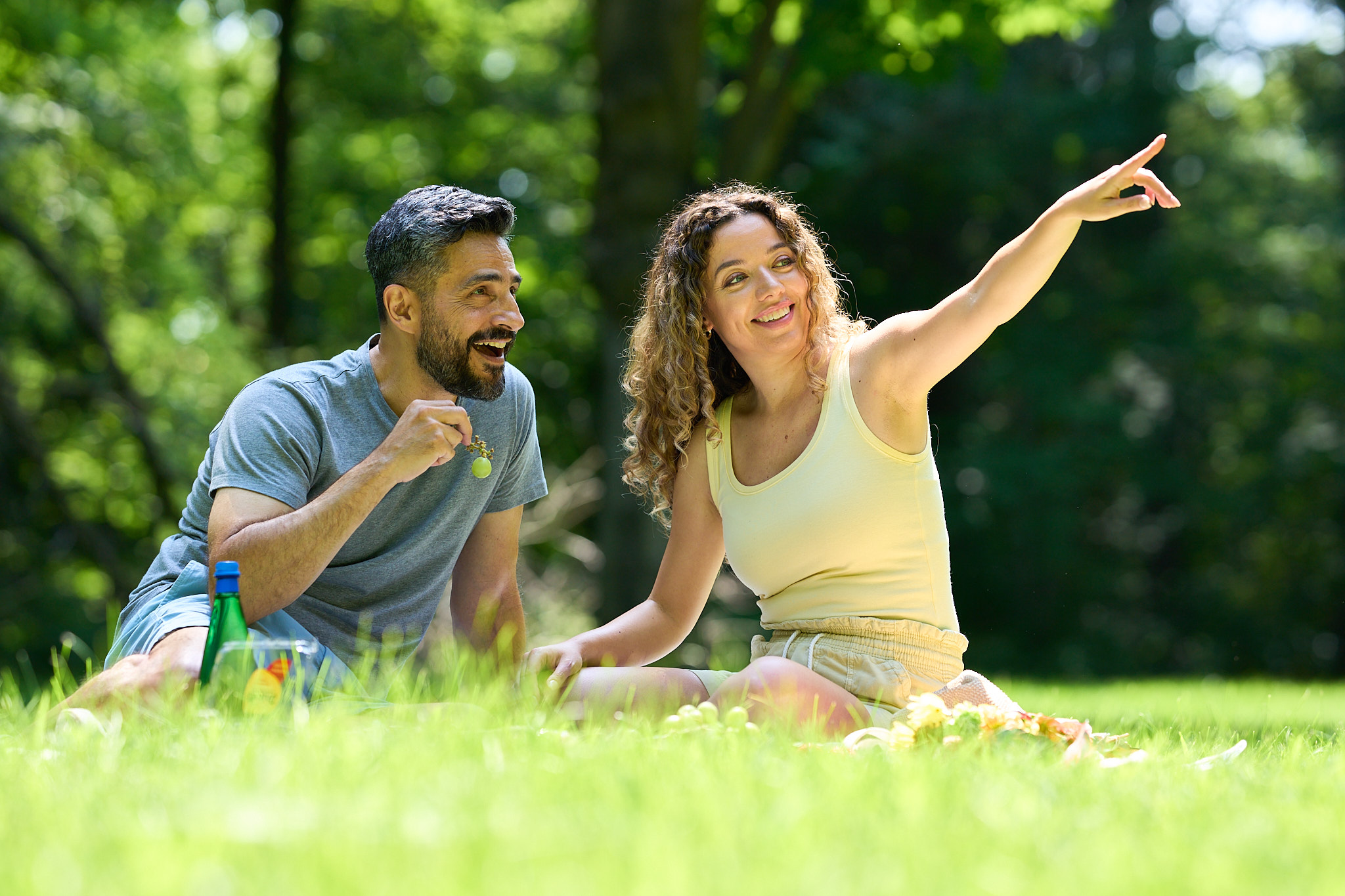Image of two adults sitting in a beautiful park enjoying a picnic.