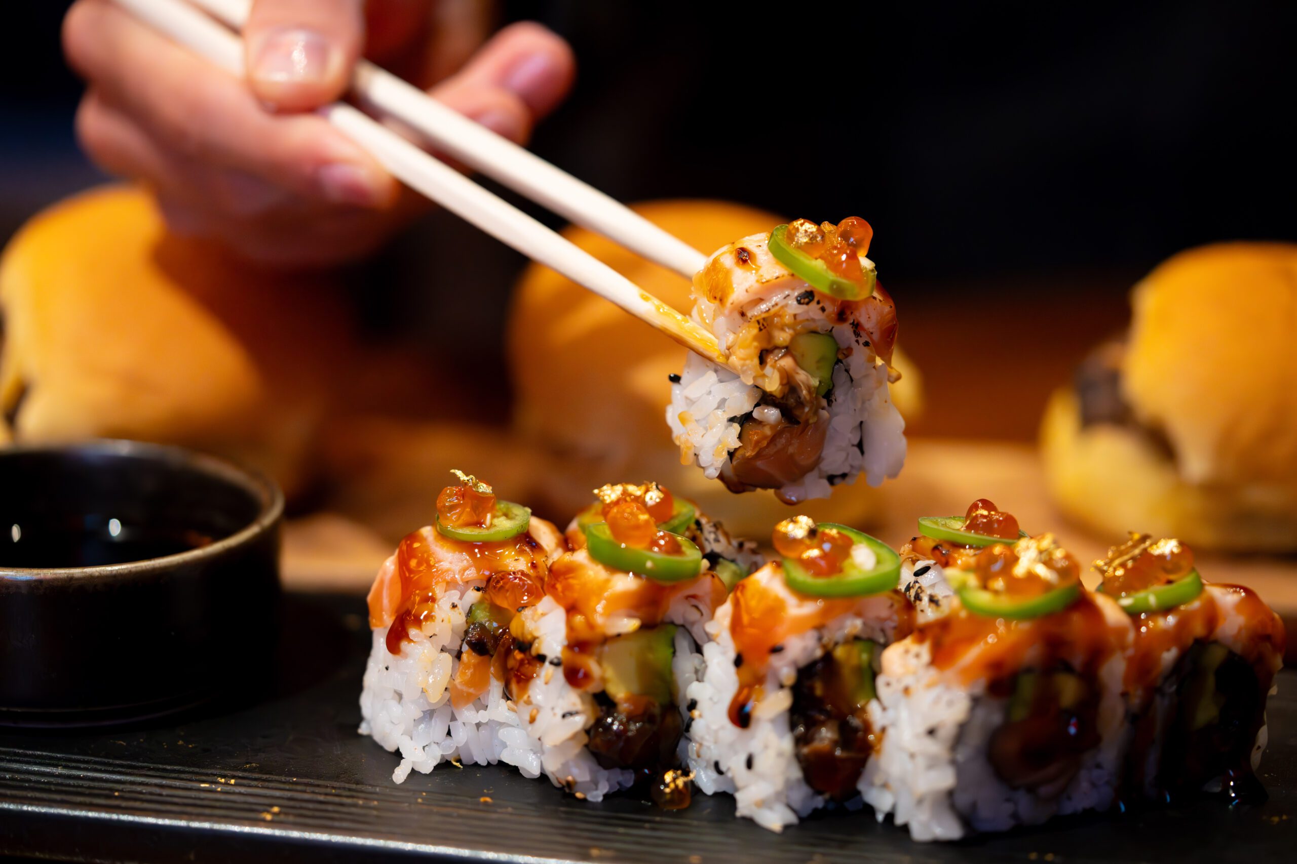 Image of a hand using chopsticks to pick up a piece of sushi