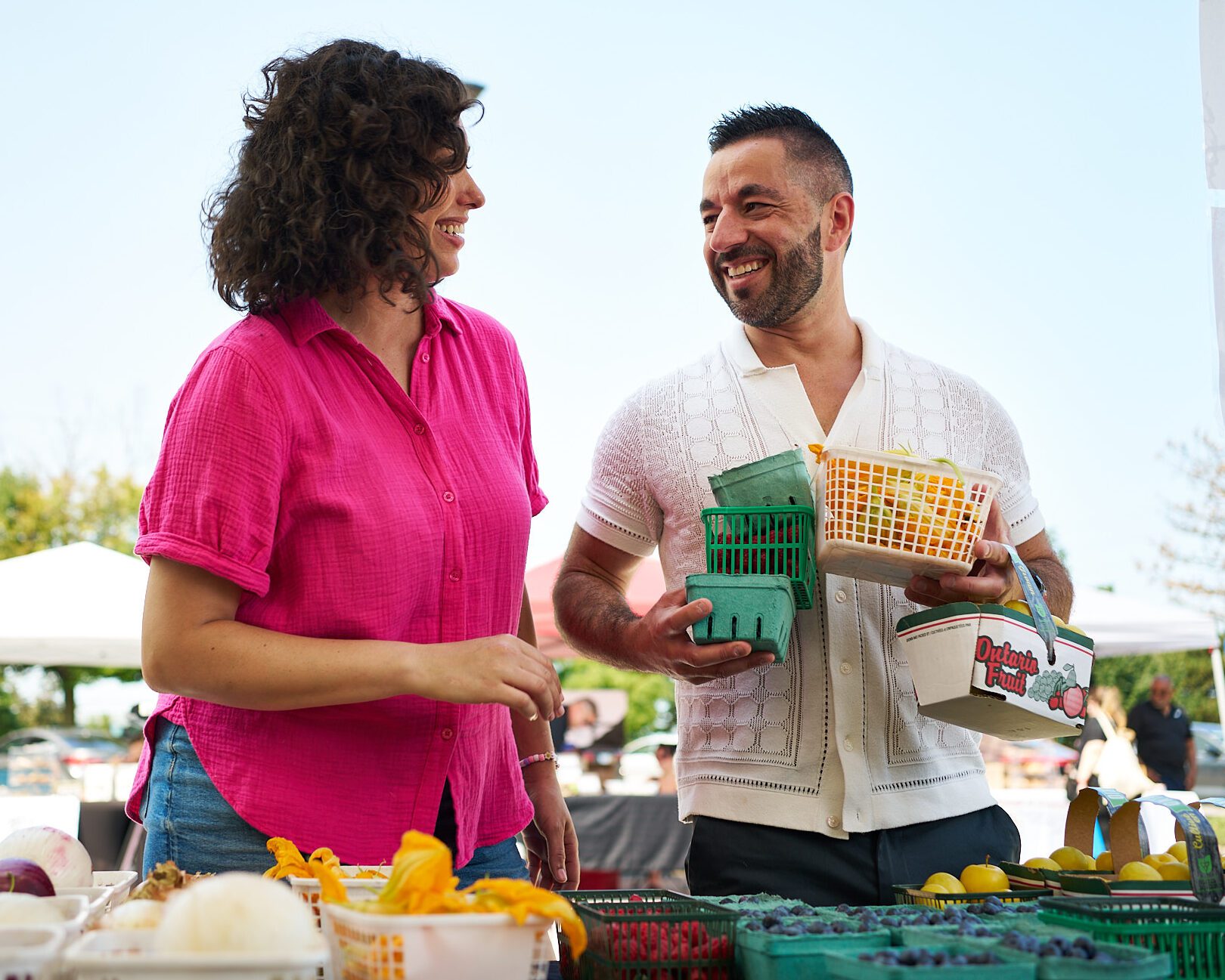 Image of two people holding fresh produce at a farmers' market.