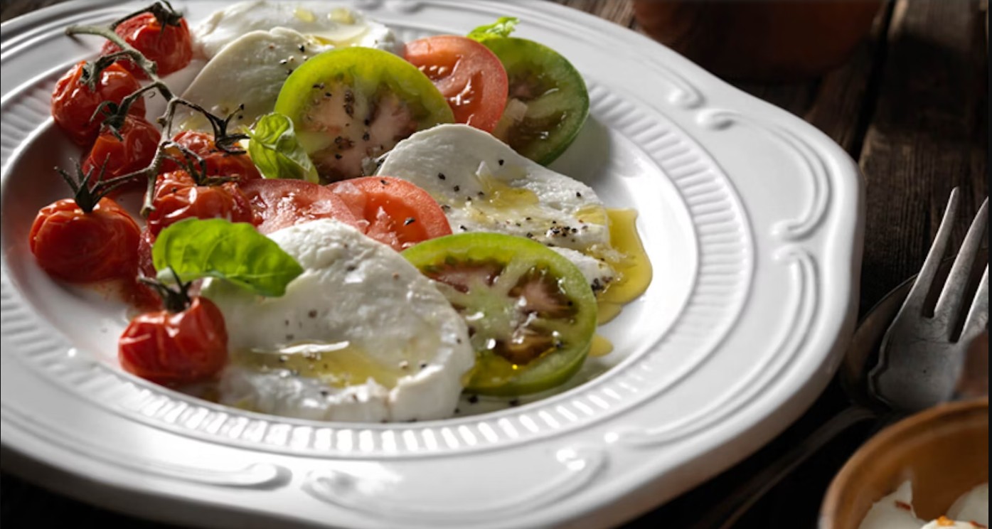 Image of a plate with heirloom tomatoes and fresh mozzarella topped with a drizzle of olive oil