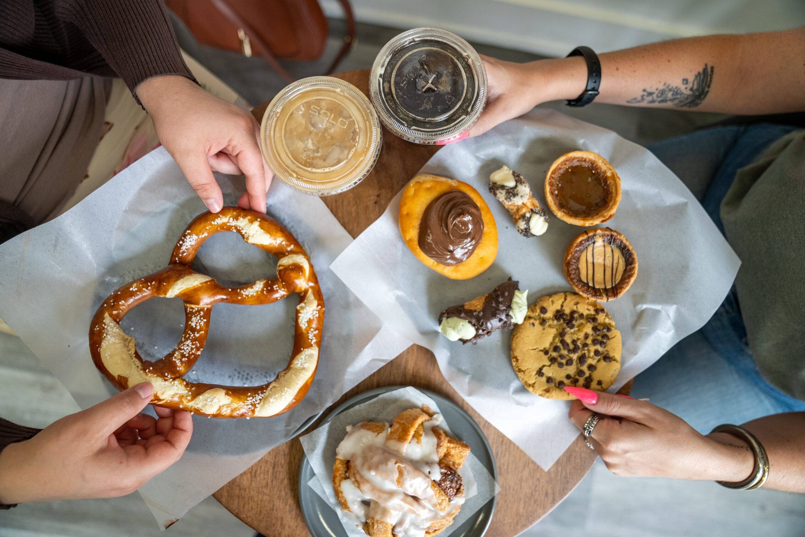 Image of a table at a bakery where two people are sitting with their baked goods and coffees enjoying them,
