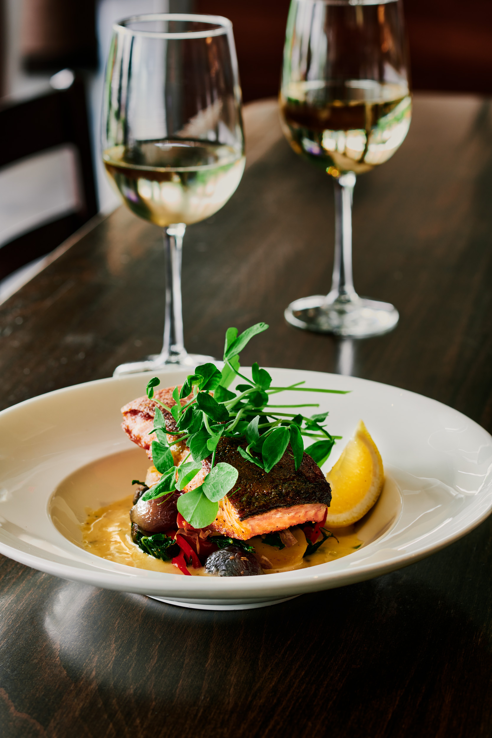 Image of a salmon dish at a restaurant with a glass of white wine beside it