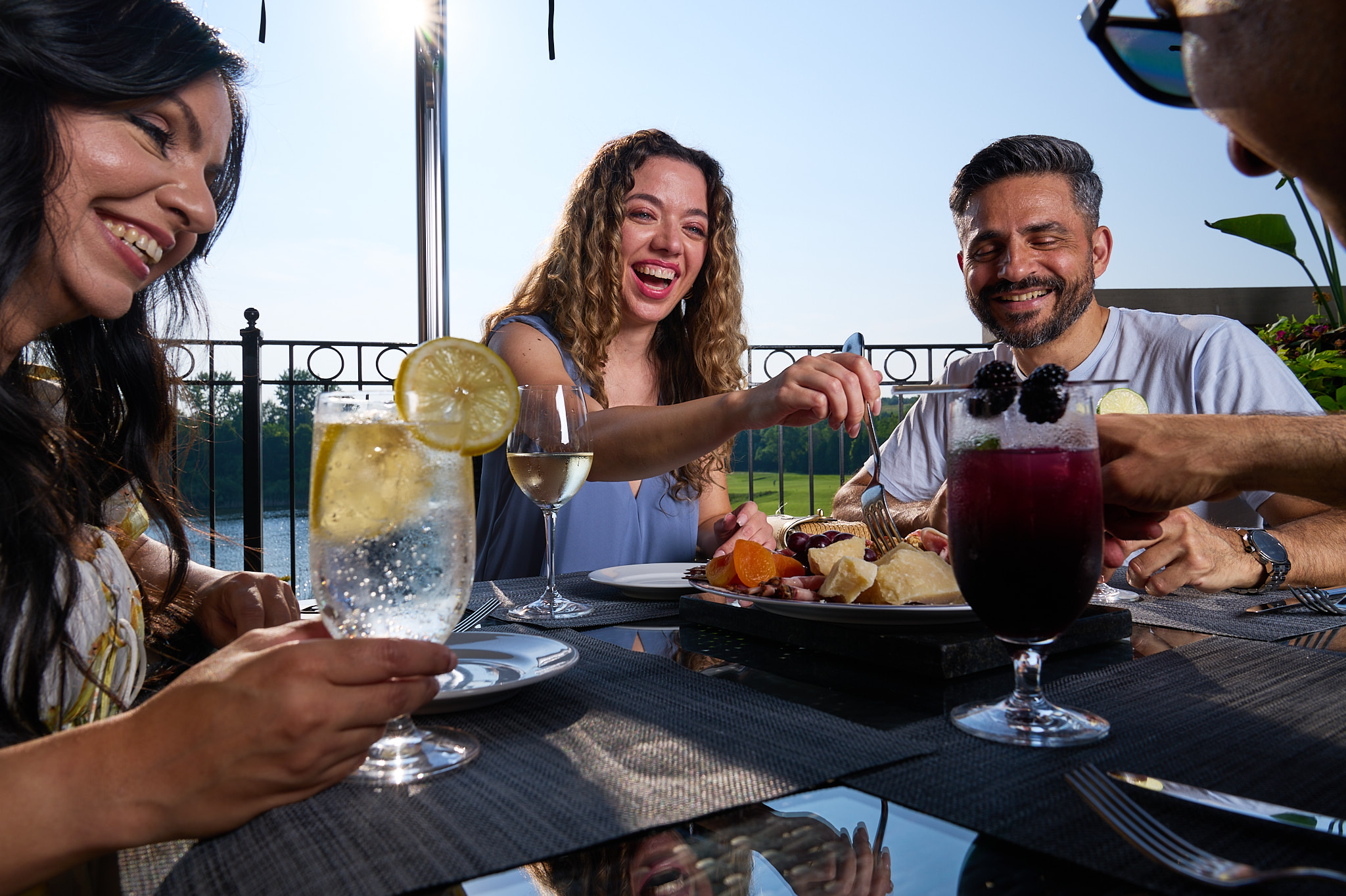 Image of three adults sitting on a restaurant patio enjoying a meal