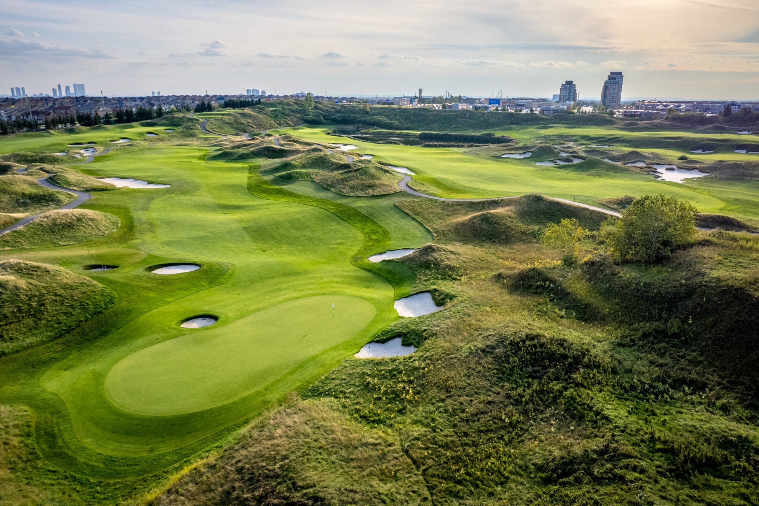 Aerial image of a golf course when a city skyline in the background